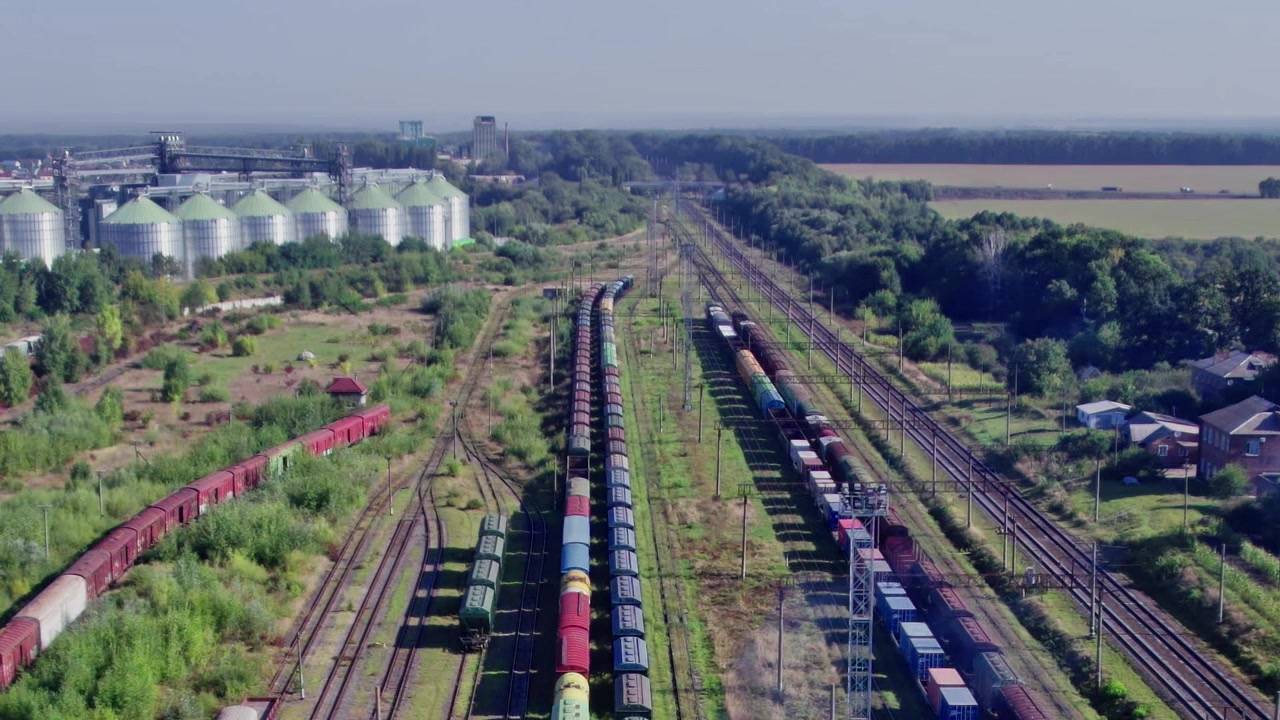 Train yard with cargo cars near factories and fields in summer