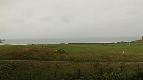 Toma-De-Timelapse-De-Golfistas-Jugando-En-El-Club-De-Golf-De-Newquay-Con-La-Playa-Fiustral-Detrás