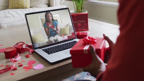 Fröhliche-Afroamerikanische-Frau,-Die-Ein-Geschenk-öffnet-Und-Einen-Videoanruf-Zum-Valentinstag-Auf-Dem-Laptop-Tätigt