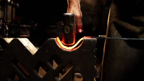 mid-section of blacksmith working on a iron rod