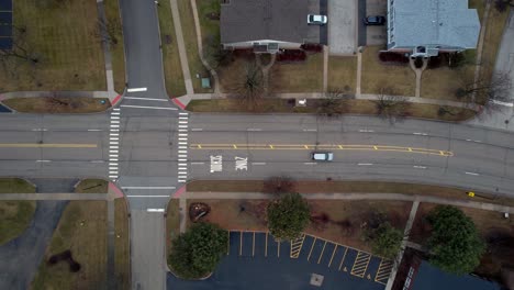 Filmische-Top-Down-Antenne,-Die-Einem-Auto-Auf-Der-Hawthorn-Pkwy-Street-Auf-Der-Schulzone-In-Vernon-Hills-Bei-Sonnenuntergang-Mit-Wohnhäusern-An-Den-Seiten-Folgt-4k-Video