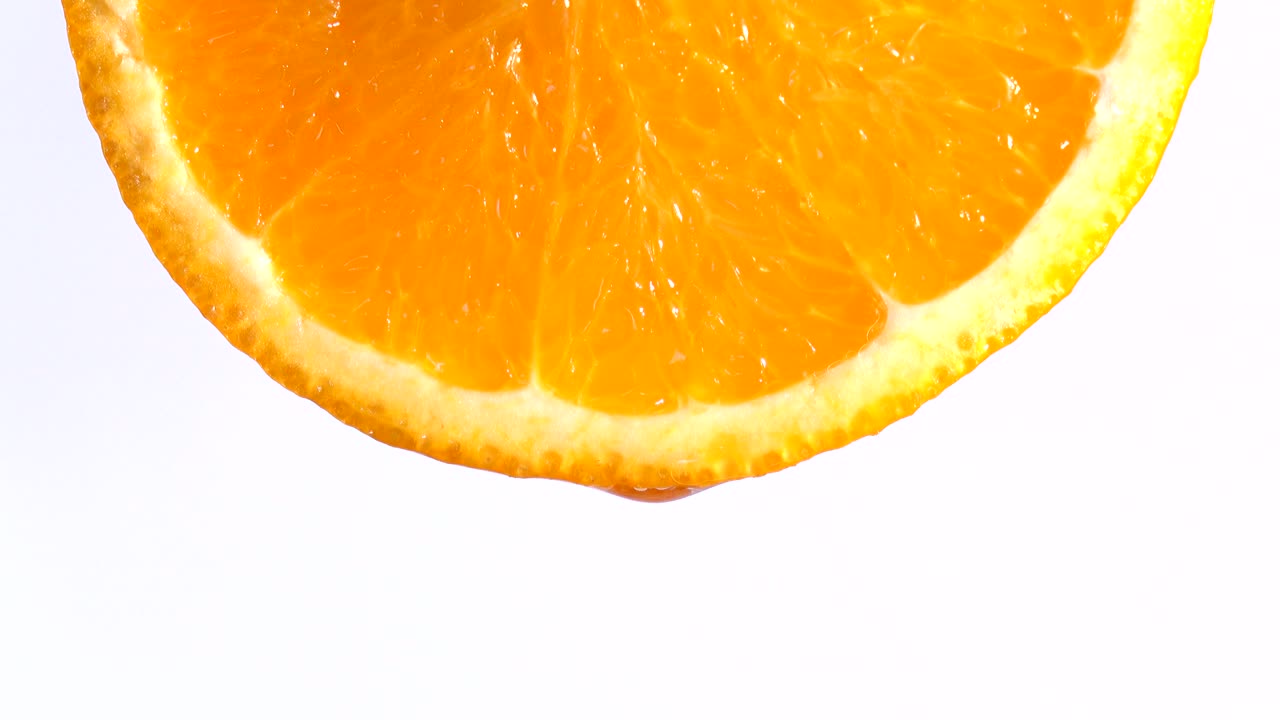 acqua o oli che cadono su una fetta di arancia, frutta per la dieta e il cibo sano