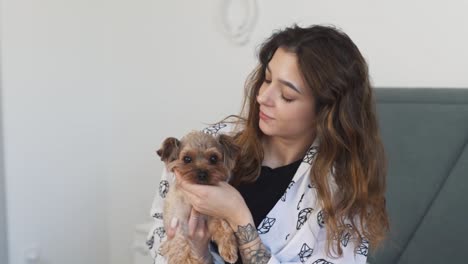 beautiful-young-woman-holds-a-Yorkshire-Terrier-in-her-arms-and-lovingly-strokes-its-face