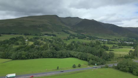 flying over busy rural highway a66 towards dark mountain blencathra on cloudy summer day