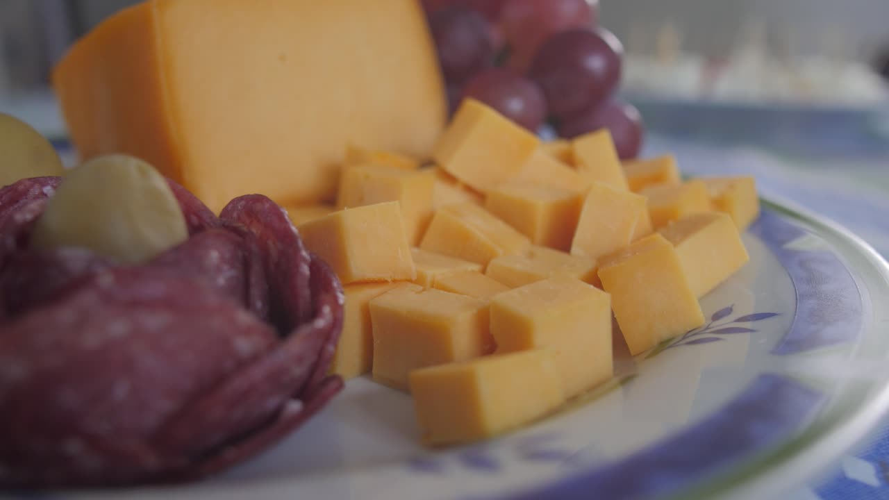 Primer plano de trozos de queso, fruta y uvas en un plato sobre la mesa