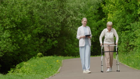 enfermera ayudando a una anciana que camina en un parque