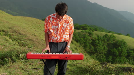 sweeping left to right pan of man playing a piano on a mountaintop