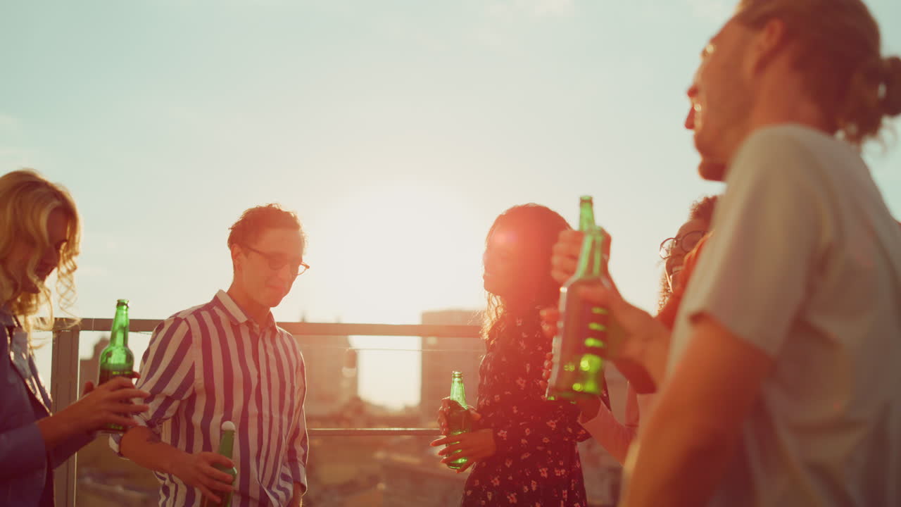 Multiethnic friends relaxing with beer at terrace. Beautiful people hanging out