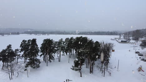 Frozen-Kaunas-lagoon-and-covered-in-white-snow-during-snowfall,-aerial-view