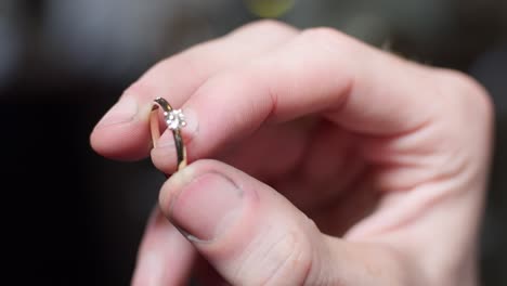 primer plano de un joyero sosteniendo un anillo de bodas de oro terminado con un gran diamante y fondo bokeh