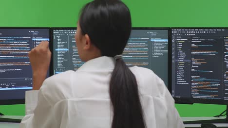 여러 컴퓨터 화면 앞에서 코딩하는 여성 프로그래머