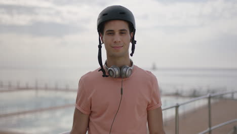 portrait-of-young-fit-man-wearing-helmet-removes-sunglasses-smiling-standing-confident-ocean-sea-side