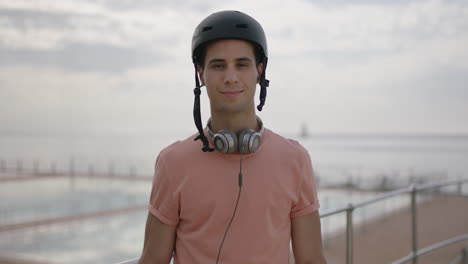 portrait of young fit man wearing helmet removes sunglasses smiling standing confident ocean sea side