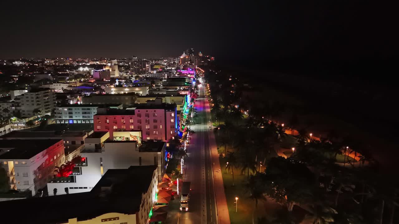 Illuminated ocean drive road in Miami south beach at night. Aerial Birds Eye shot. Lighting buildings and rooftops of bars and restaurants. Palm trees and dark ocean. Florida, USA