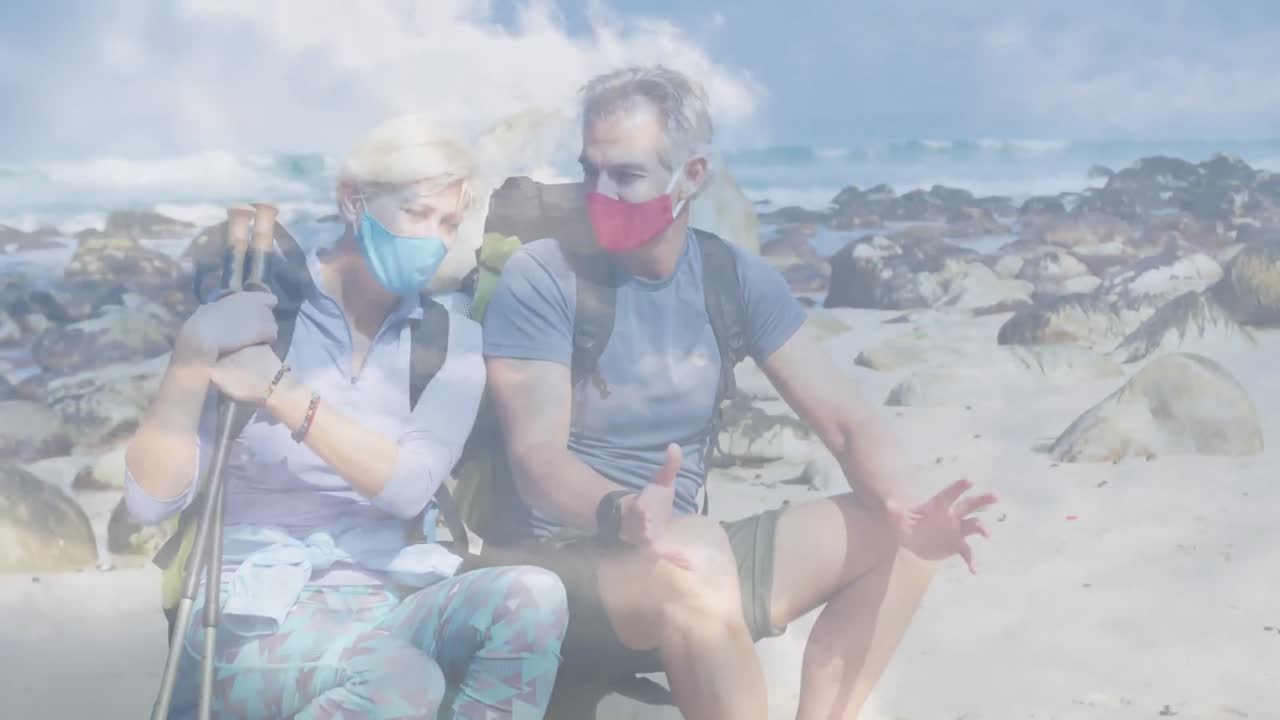 행복 한 백인 노인 부부 가 해안 에서, 빠르게 움직이는 구름 위 에서 하이킹 하고 있다