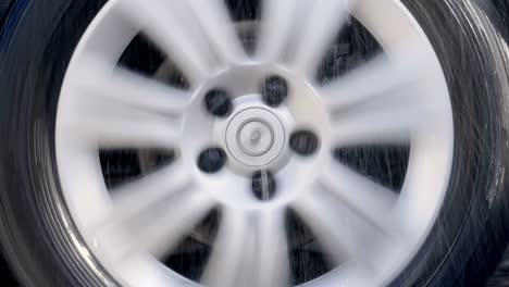 car wheel with shiny silver rim rides in the rain drops and strong shaking