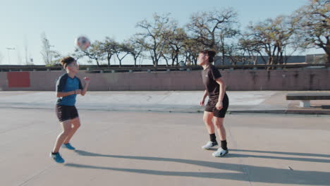 two female soccer players juggling and passing ball on the street