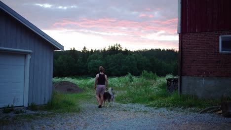rear of a man walking with his dog in a rural village during sunset