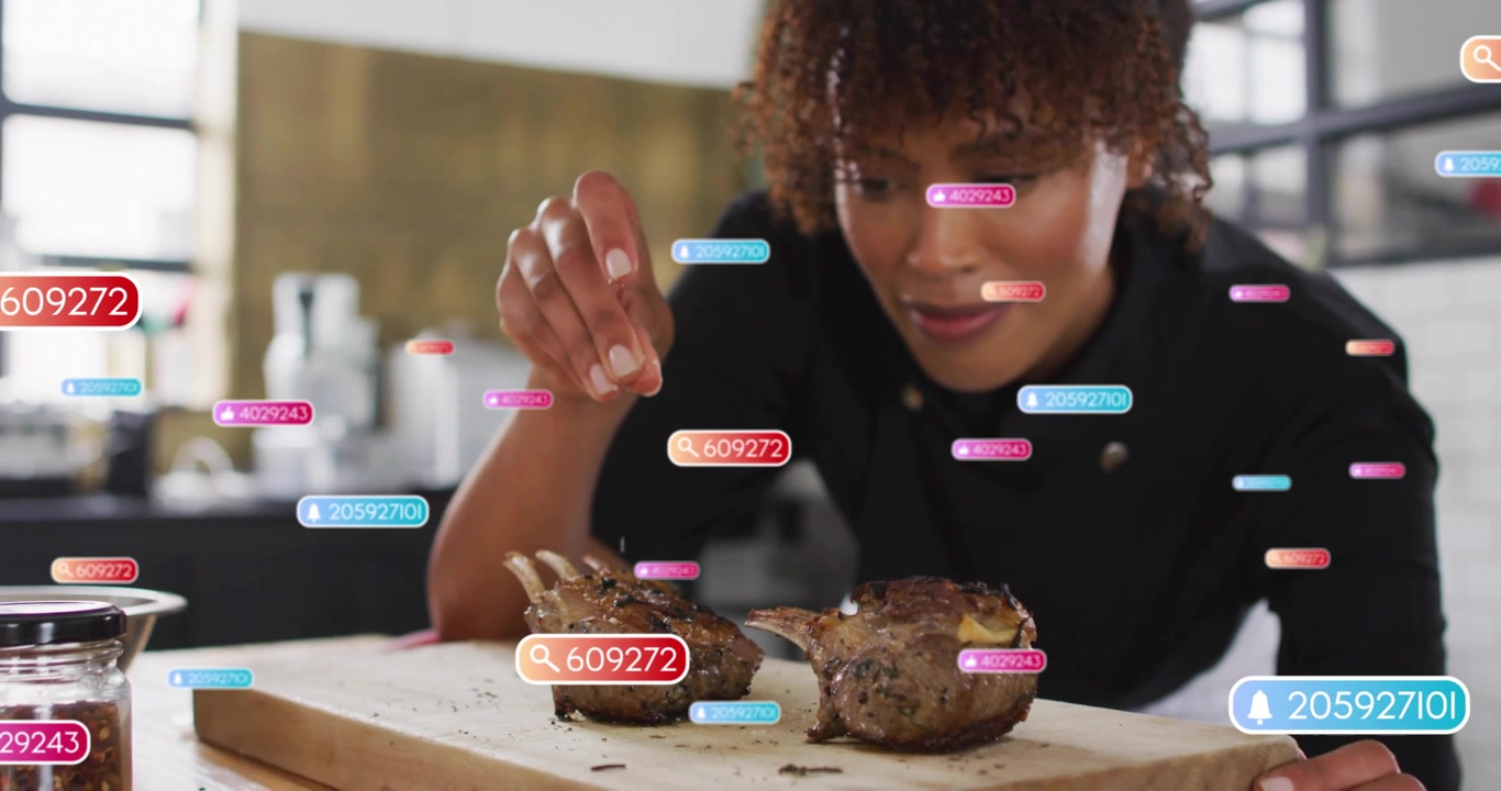 Chef picking up metal shaker and evenly seasoning lamb racks while digital food tags rising