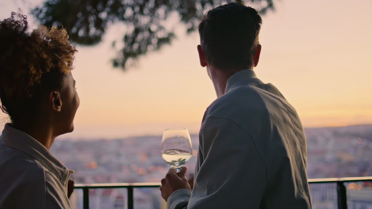 만적 인 커플이 이야기하는 해가 지는 도시 풍경 클로즈업. 곱슬한 여자 손가락을 가리키고