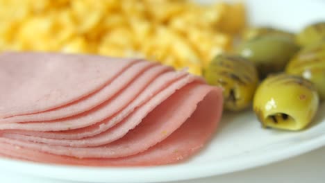 plato de desayuno con jamón, huevos revueltos y aceitunas