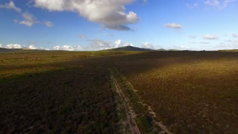 Aerial-view-of-a-dirt-road-winding-through-mountainous-terrain