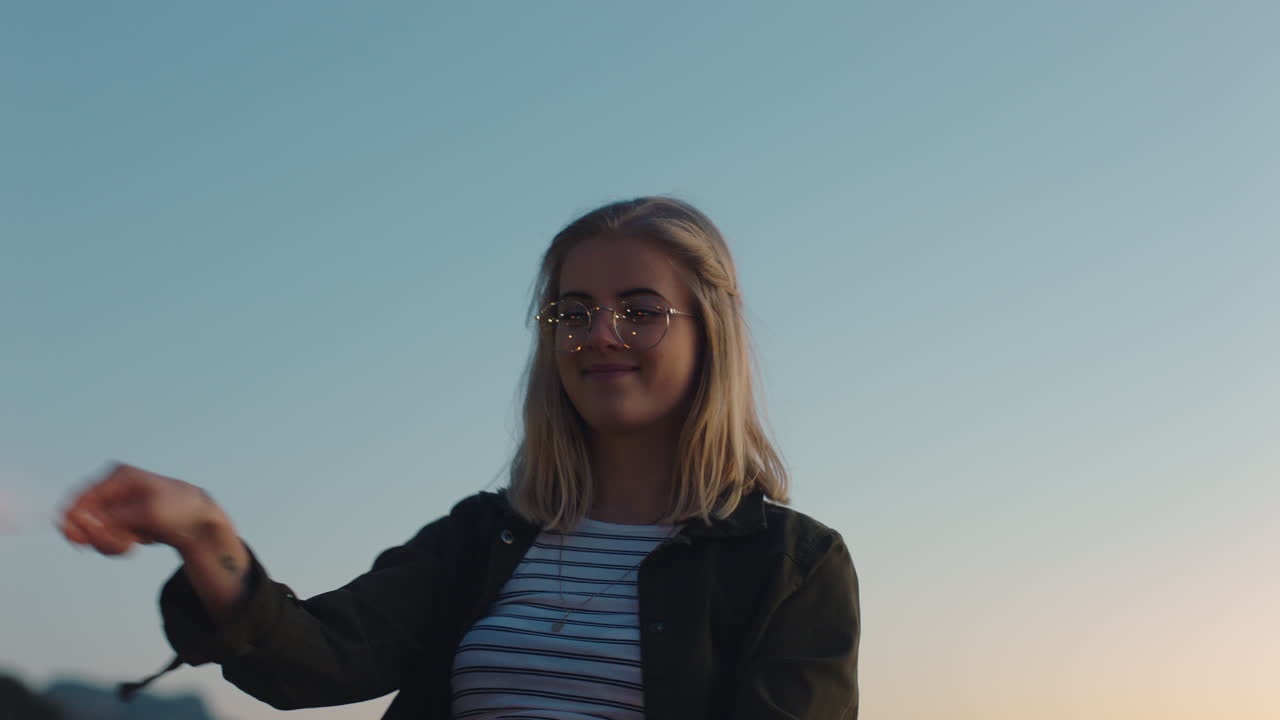 adolescente feliz brincando com faíscas na praia ao pôr do sol se divertindo comemorando a véspera de ano novo mulher aproveitando a celebração do dia da independência com fogos de artifício