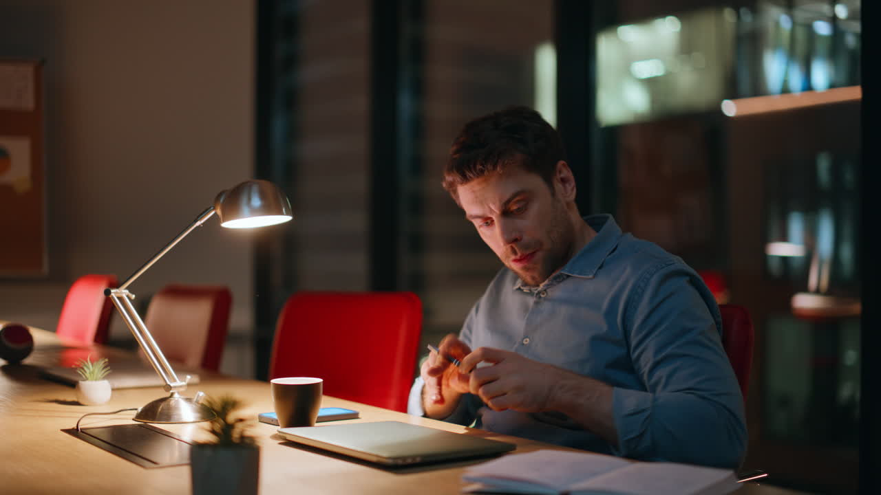 Accountant writing notebook night office under lamp light closeup. Serious man