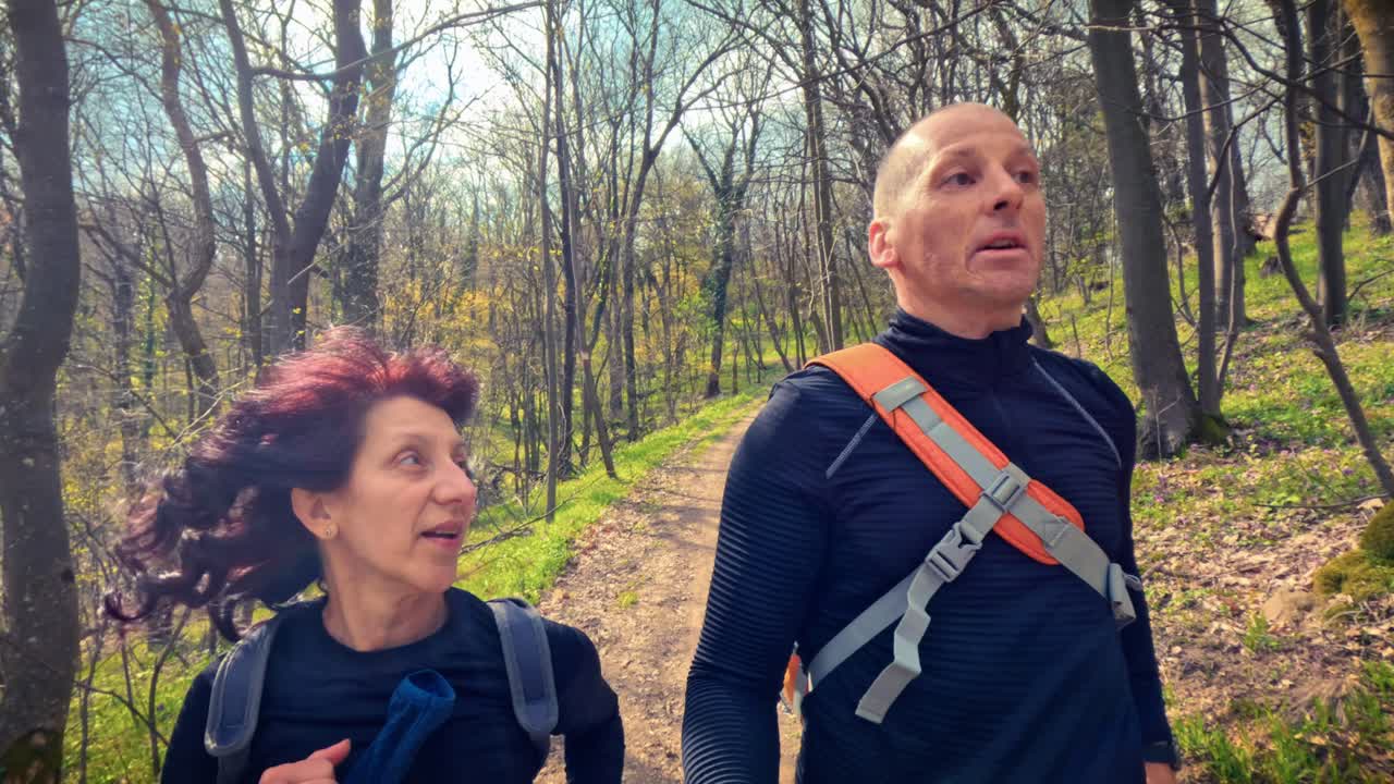 Coppia matura e autentica che passeggia in una foresta primaverile in fiore. Promuovendo la salute mentale, la mindfulness e il potere calmante della natura per il sollievo dallo stress e la pace.