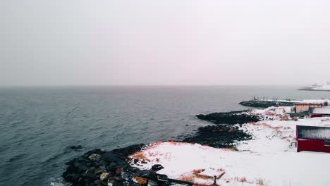 aerial view of black sand on the coast of the barents sea, on a dark, wet, winter day, in troms, nordland, north norway - descending, drone shot