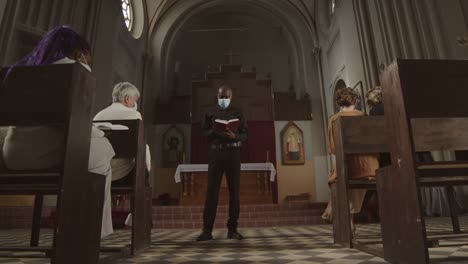 priest wearing mask preaching sermon in christian church