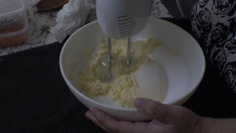 electric mixer being used in bowl to whisk butter and sugar