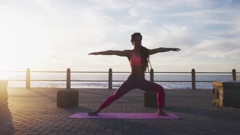 african american woman in sportswear doing yoga on promenade by the sea