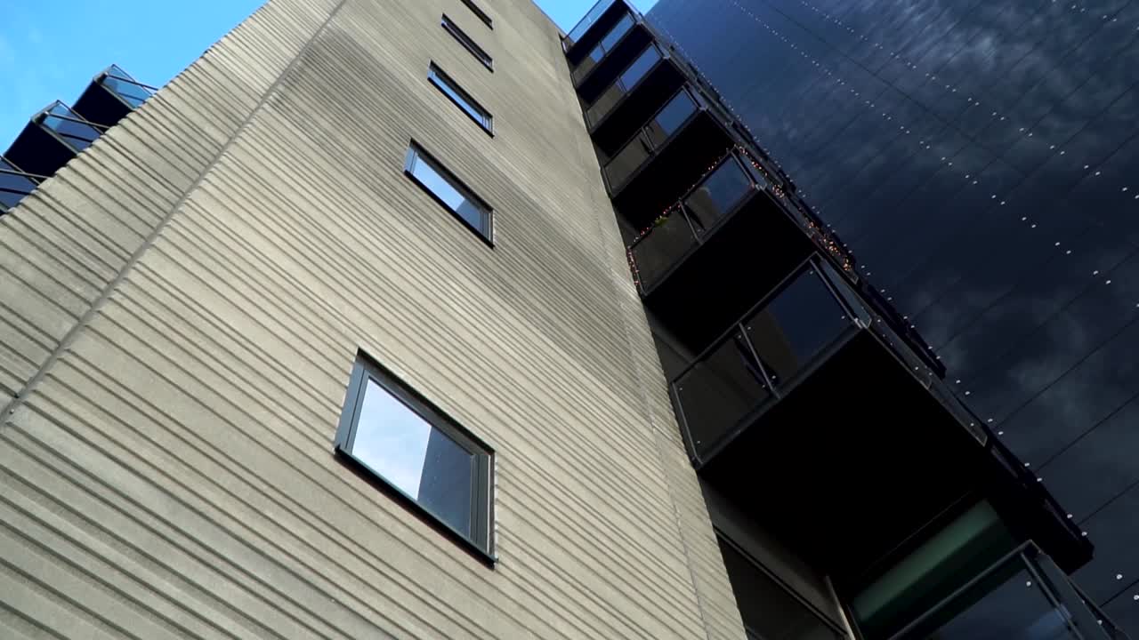 Slow motion tilt view moving towards the top of a building in bright daylight.