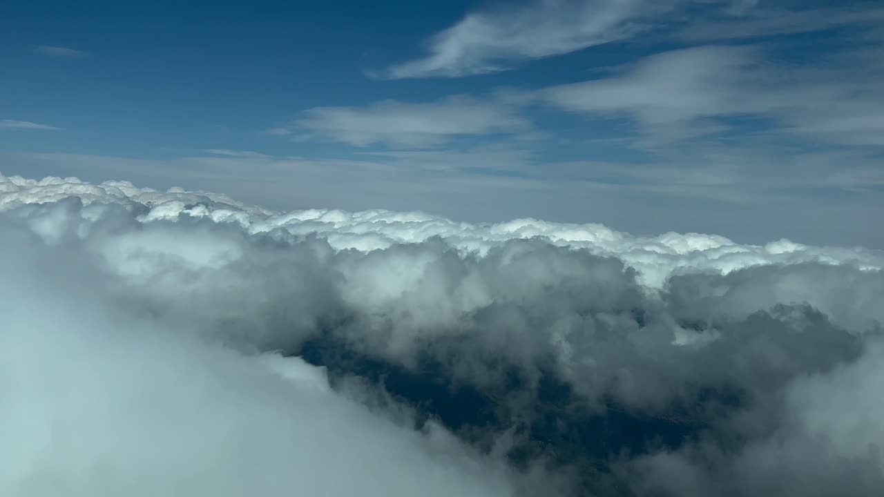 POV cloudscape shot from an airplane cockpit in a left turn over some flufly clouds