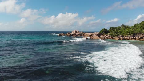 aerial view following the waves rolling towards the unpeopled, white beaches at anse coco, petit anse and grand anse on la digue, an island of the seychelles