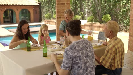 multi-generational family celebrating father's day with an outdoor meal by the pool