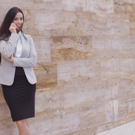 pretty woman talking on phone and leaning on wall