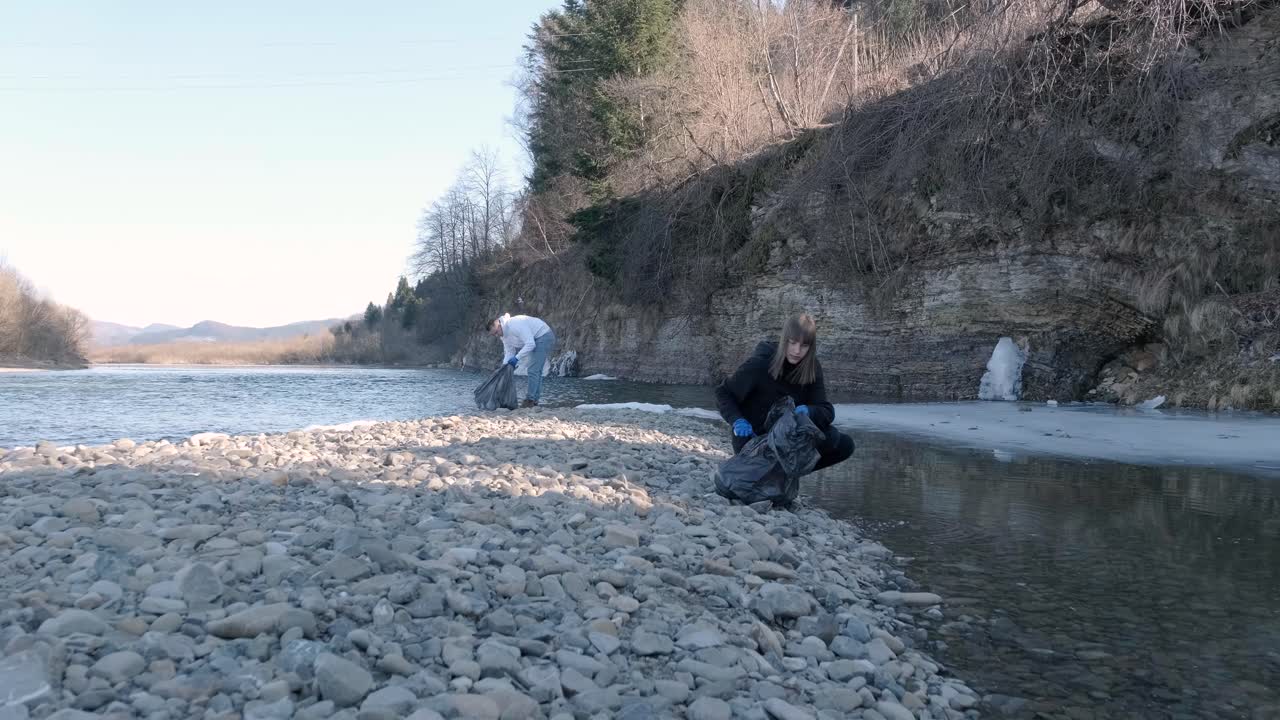 해변에서 플라스틱을 청소하는 팀워크: 자원봉사자들이 쓰레기 봉투에 쓰레기를 모으고, 플라스티크 오염과 환경 문제 개념: 플래스틱에서 자연을 자발적으로 청소하는 것, 지구를 녹색화하는 것