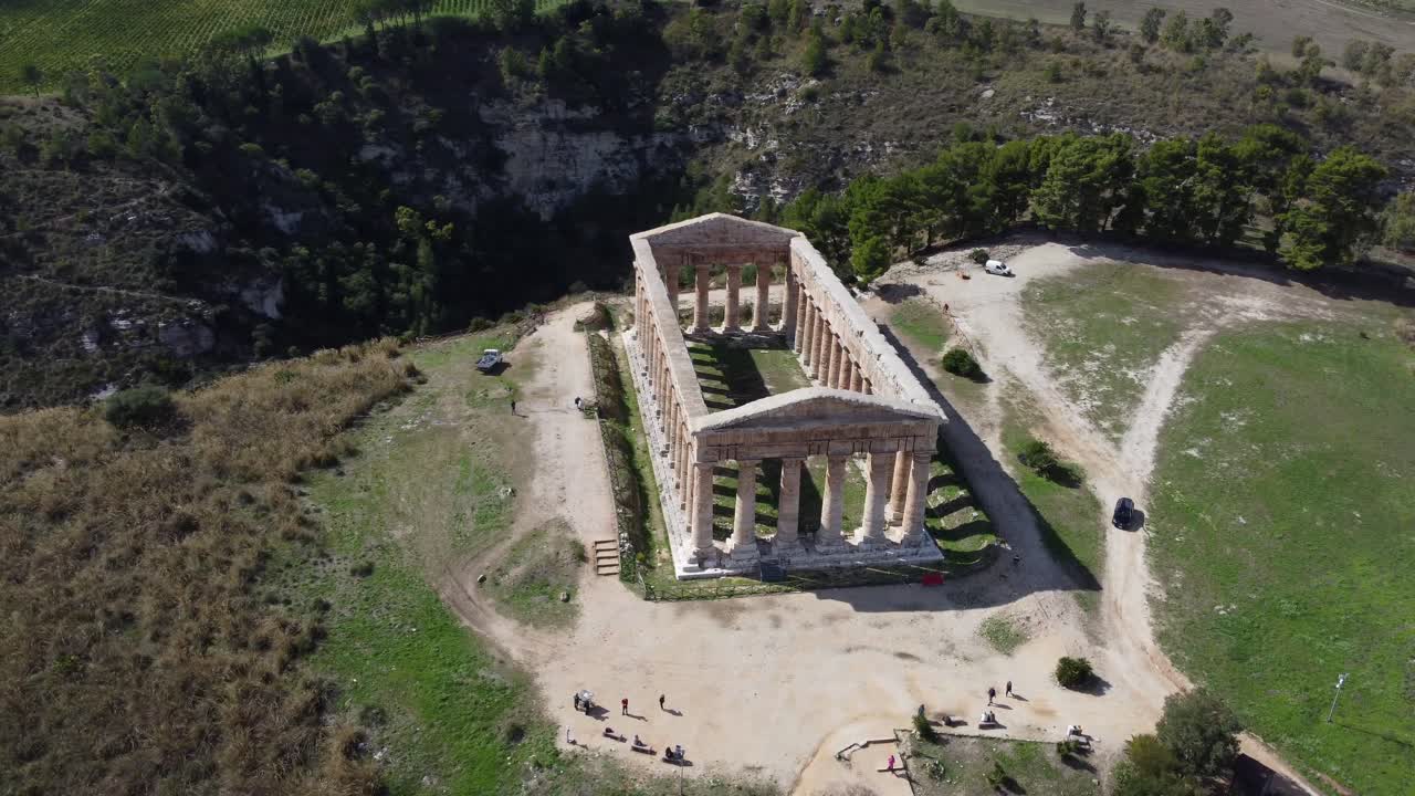lento giro aéreo de un antiguo templo griego a la luz del sol con un desfiladero exuberante