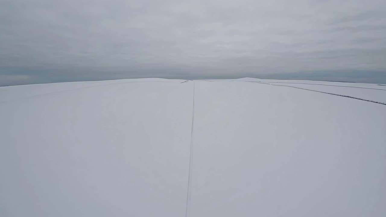 Aerial video captures a vast, snow-covered landscape from a high angle, showcasing a minimalist