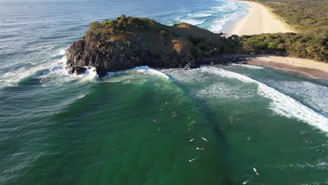 Surfers-Floating-In-The-Ocean-At-Cabarita-Beach-In-New-South-Wales,-Australia---aerial-drone-shot