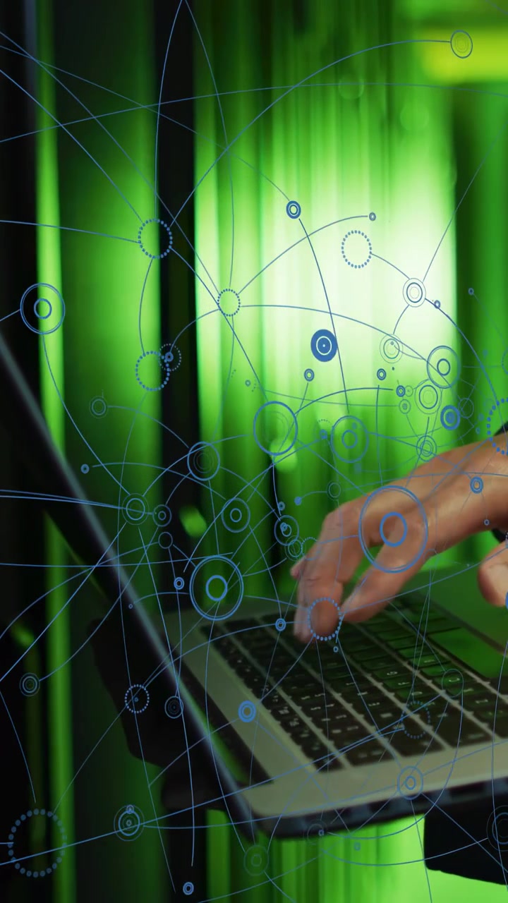 Vertical video: Right hand nearing laptop igniting blue network overlay as tech typing showing data
