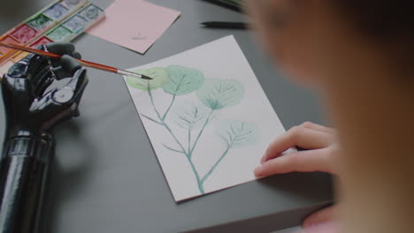 Woman with Prosthetic Arm Painting at Desk