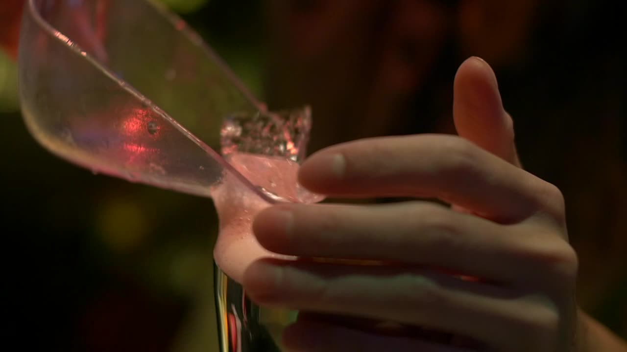 el hielo se saca de la cuchara y se coloca en una mezcla de cóctel fresca filmada como un primer plano en cámara lenta