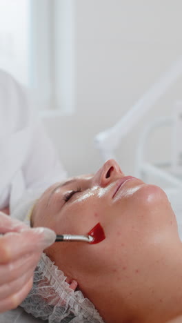 esteticista aplicando un suero de ácido hidratante especial pelando la mejilla de la mujer joven en la clínica