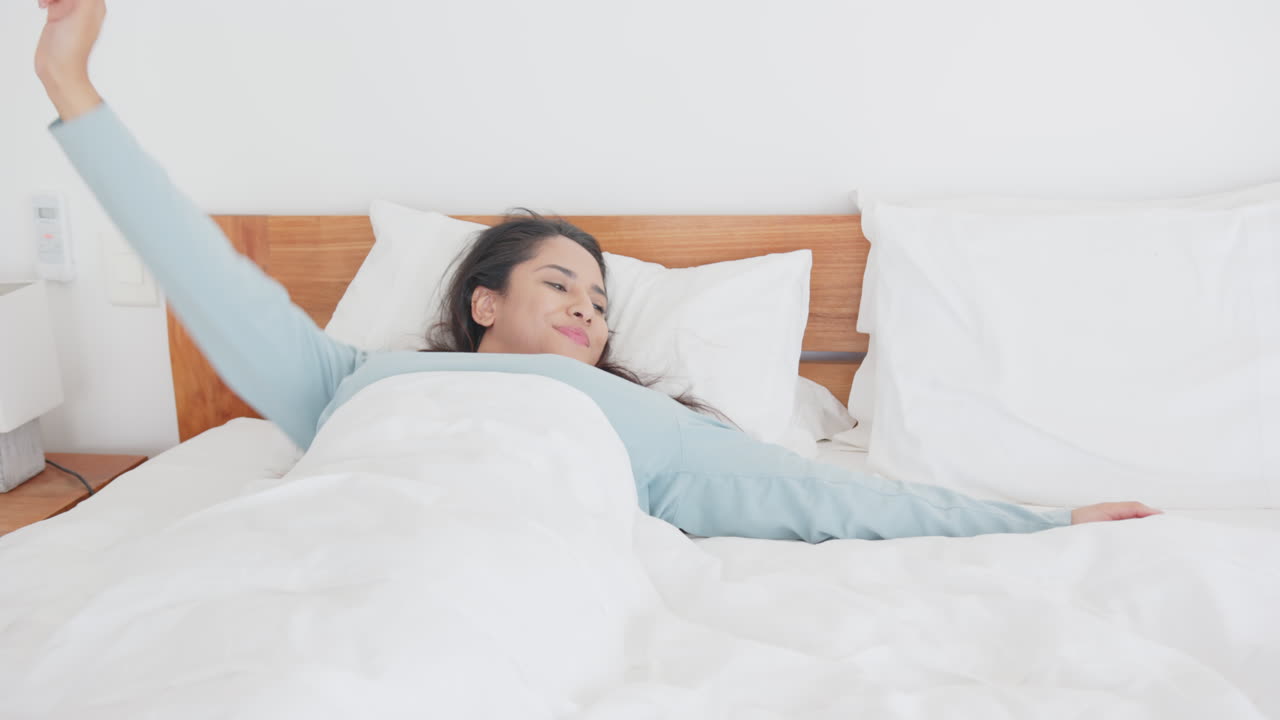 Stretching in bed, asian woman waking up and starting her day with smile, at home