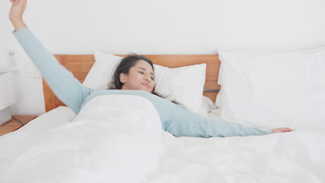 stretching in bed, asian woman waking up and starting her day with smile, at home