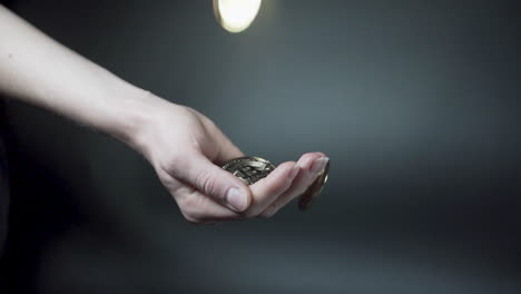 Hand-catching-falling-golden-cryptocurrency-coins,-black-background