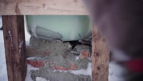 el hombre está usando pequeñas rocas y cemento para llenar los huecos debajo de la bañera de agua caliente diy - de cerca